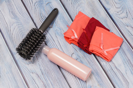 Bottle of shampoo, a comb and women folded cotton panties on a wooden background. Women cosmetics...