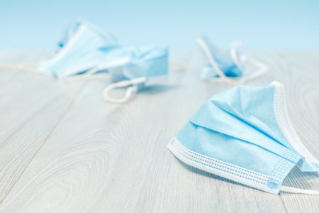 Close-up view of used medical protective masks lying on a floor. Utilization of individual protection means during of pandemic. Pollution of environment.の写真素材
