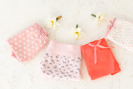 Women's folded cotton panties with buds of daffodil flowers on the white structured background....