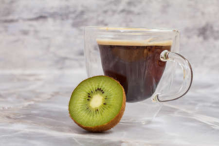 Glass cup of coffee and a kiwi fruit on the kitchen table.の写真素材