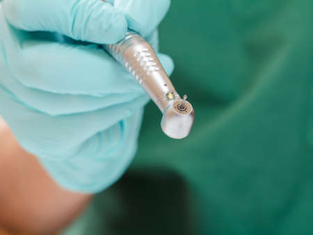 Dentists hand in glove with dental handpiece.の写真素材
