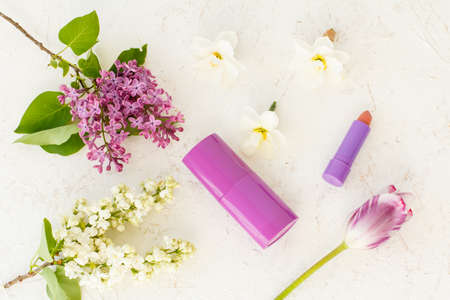 Woman deodorant, a lipstick, buds of daffodil flowers, tulip and lilac flowers on the white structured background. Woman cosmetics. Concept of giving a gift on holidays. Top view.の写真素材