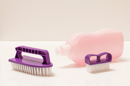 Bottle of washing liquid and plastic brushes on the white tiled floor. Washing and cleaning concept.の写真素材