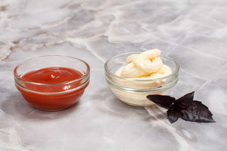 Set of sauces - glass bowls with ketchup and cheese sauce on the kitchen table.. Top view.の写真素材