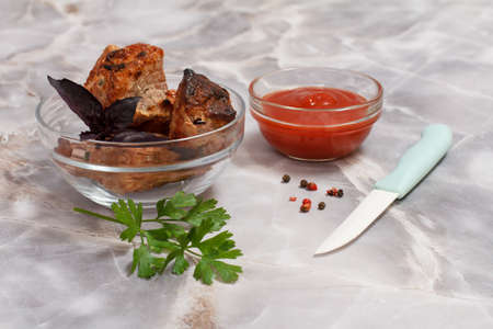 Grilled pork in a glass bowl with fresh parsley and tomato sauce in a glass bowl.の写真素材