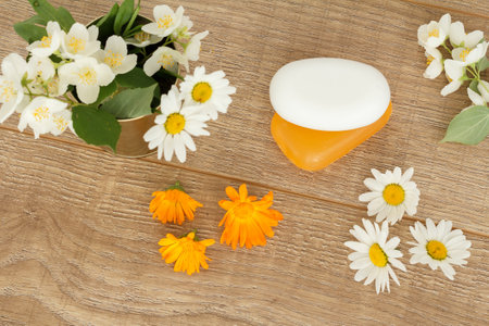 Soap with white chamomile flowers and yellow marigold flowers on the wooden desktop. Top view.の写真素材