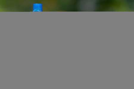 Bottles of dishwashing liquid, brush in a basket and garbage bags.
