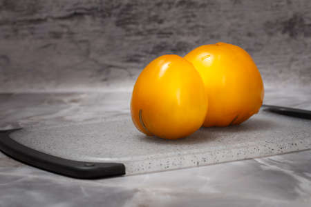 Ripe tomatoes on cutting board with gray background.の写真素材