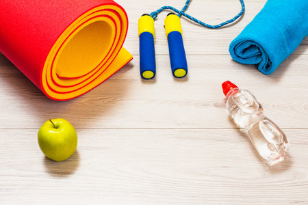 Yoga mat and skipping rop for fitness, a towel, a bottle of water, an apple in a room or a gym on...