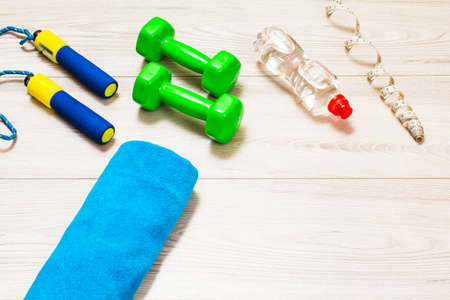 Skipping rop and dumbbells for fitness, a towel, a bottle of water and a tape-measure in a room or a gym on the gray floor.の写真素材