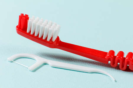 Close-up view of a toothbrush and a silicone flossing toothpick on the blue background. Shallow depth of field.の写真素材