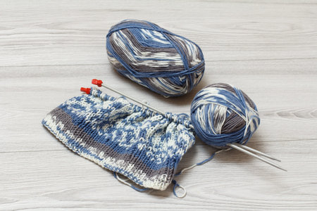 Just started pullover and skeins of yarn with metal knitting needles on the gray background....