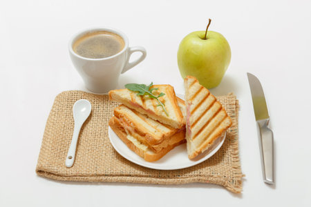 Homemade grilled cheese sandwich for breakfast on a plate with a spoon and a knife, a cup of coffee...