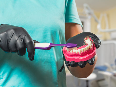 Close-up view of dentist's hands in latex gloves with a layout of the human jaw and a curette....