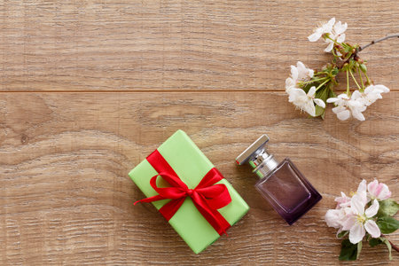 Gift box, a bottle of perfume with branches of flowering cherry and apple trees on the wooden...
