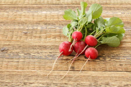 Ripe red radishes with green stalks on the old wooden boards. Top view. Spring harvesting of vegetables in a garden.の写真素材