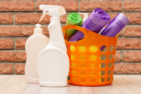 Bottles of dishwashing liquid, basket with garbage bags and sponges.