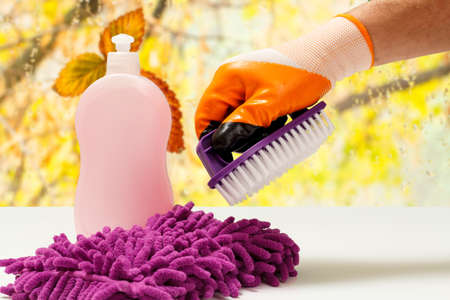 Close-up view of the man's hand in a rubber protective glove with a plastic brush on the blurred background. Washing and cleaning concept.の写真素材
