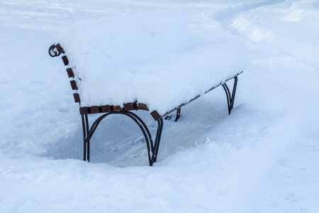Bench covered with snow in snowbound city in winter. Winter timeの写真素材