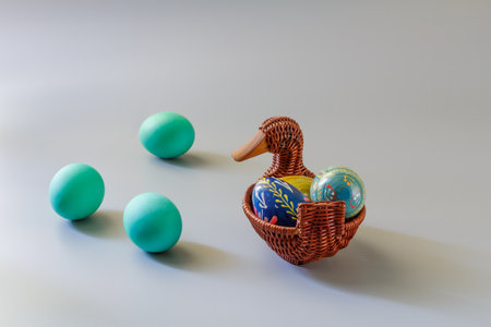 Colorful Easter eggs in the wicker basket on the gray background.の写真素材