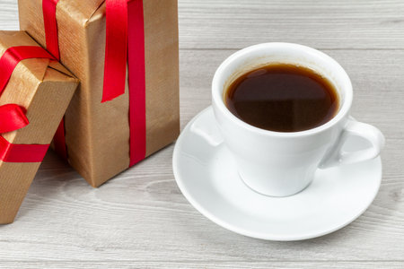 White cup of coffee and gift boxes on the gray wooden background.の写真素材