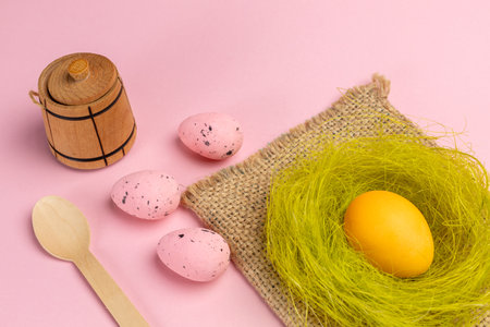 Colored Easter eggs and wooden utensils and cutlery with the pink background. Top view.の写真素材