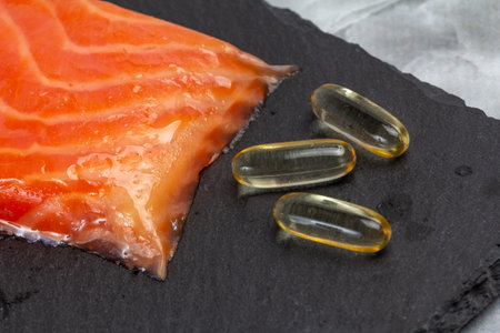 Fillet of raw salmon fish and capsules with fish oil on the cutting board. Top view.の写真素材