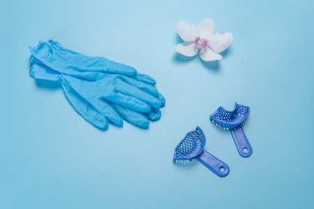 Blue latex gloves and dental flexible impression trays on the blue background. Top view.の写真素材