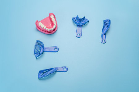 Set of dental flexible impression trays with a layout of the human jaw on the blue background. Top...