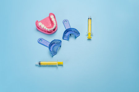 Dental flexible impression trays with a layout of the human jaw on the blue background. Top view with a copy space.の写真素材