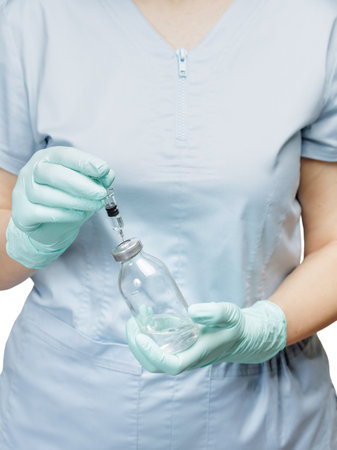Glass bottle for liquid medicine and a plastic syringe for injection in hands in latex gloves.の写真素材