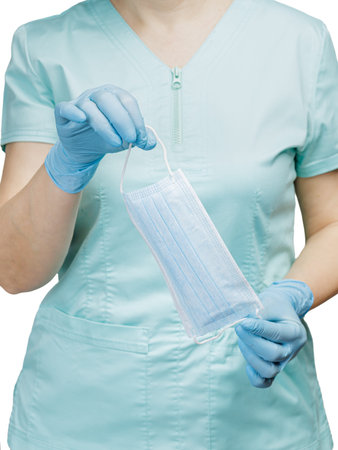 Hands of a female doctor in latex gloves holding a medical mask. Selective focus on the mask.