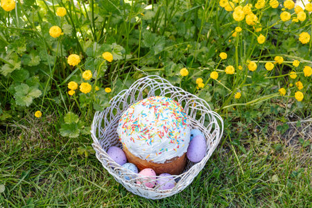 Sweet Easter cake and colorful Easter eggs in the wicker basket with green grass on the background. Top view.の写真素材