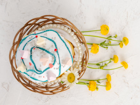 Sweet Easter cake in the wicker basket and yellow Ranunculus asiaticus on the white background. Top view.の写真素材