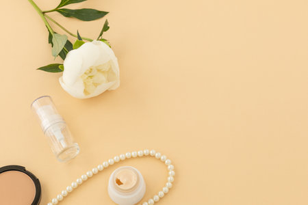 Facial serum, cream, a box with powder and beads on the beige background. Women cosmetics and accessories. Top view.の写真素材