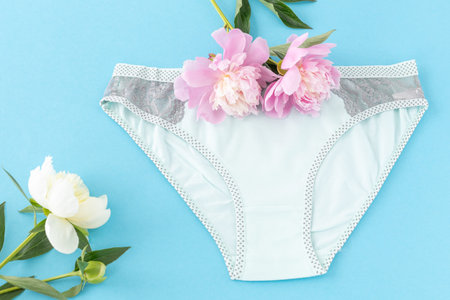 Bikini-brief style cotton panties with peony flowers on the blue background. Women lingerie. Top...