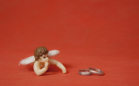Two silver rings with angel in red backgroundの写真素材