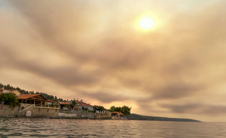 The sun barely peeks out of the clouds from forest fires on a hot day in Greece, Kassandra peninsulaの写真素材