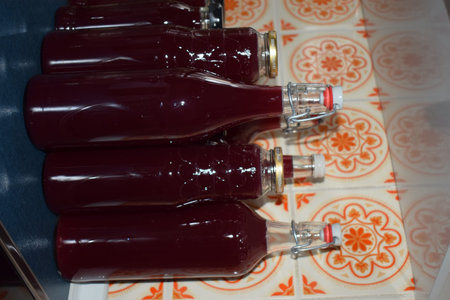 Bottles of dark red grape juice on a table in a restaurant, close-up
