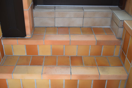 Staircase in the house with orange tiles and wooden door.の写真素材