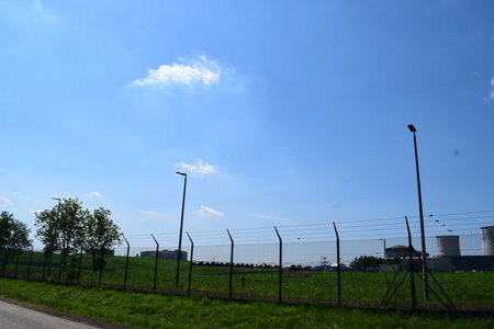 Power plant in the middle of the field with green grass and blue skyのeditorial素材