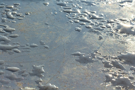 on a blue clad tile gleams a drop of water and ice in the sunの写真素材