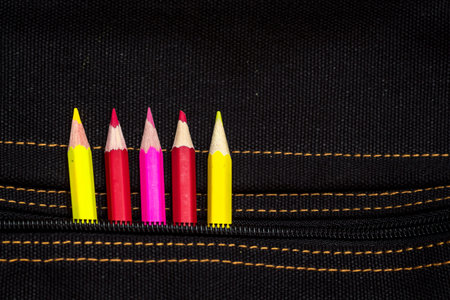 pencils of red, yellow and pink color peep out of the pocket of the bagの写真素材