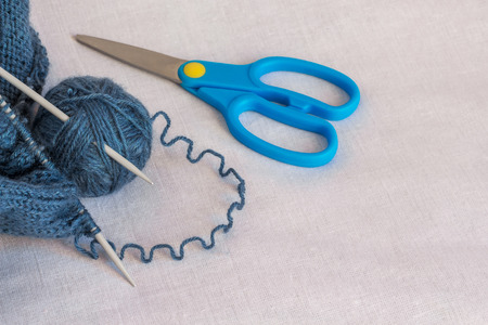 a hank of thread for knitting, knitting needles and a scissors, on the right an empty seatの写真素材