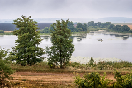 summer landscape: a river with a boat, a sky covered with cloudsの写真素材