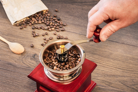 Grinding coffee on an old handmade coffee grinderの写真素材