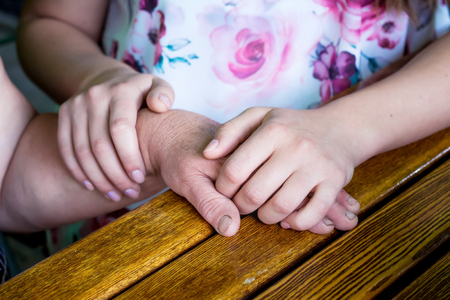 The daughter holds the mother's hand in her hands. The daughter comforts the sick mother. Daughter expresses gratitude to her mother. Support for the elderlyの写真素材
