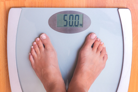 Girl on weighing. Perfect weight for a girl. Libra shows that a girl weighs 50 kg. Weight controlの写真素材