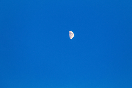 The moon on a clean blue sky in a bright eveningの写真素材