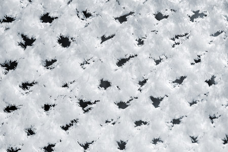 Metal mesh fence, covered with fluffy frost in the winter morning